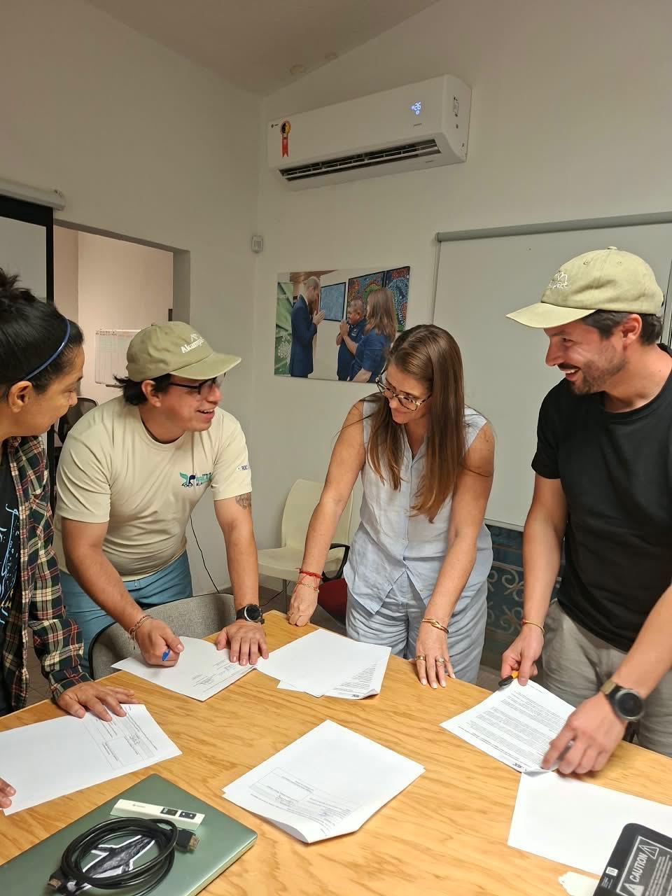 Equipos de ROC y Akampa revisan y firman documentos alrededor de una mesa